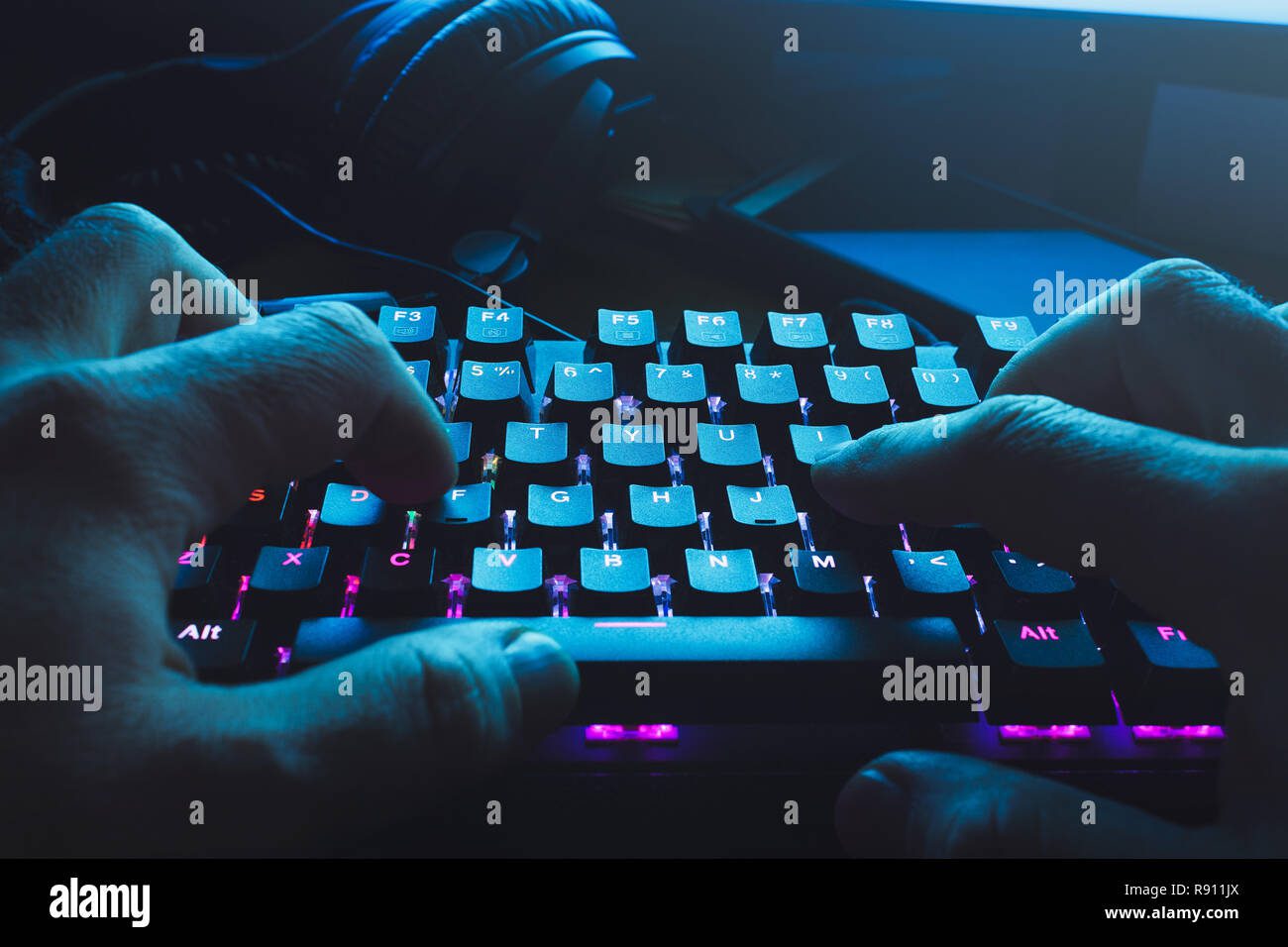 Manos tecleando teclado iluminado